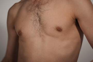 Closeup of a man's chest. His chest hair is in focus, showing natural body hair on a thin, athletic man with olive complexion. The photo feels intimate, expressing male body image and self-confidence.