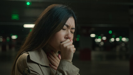 Unhealthy sick Asian woman coughing flu symptom allergy chinese japanese girl female stand in cold dark parking underground korean lady with painful sore throat cough covid infection health problem