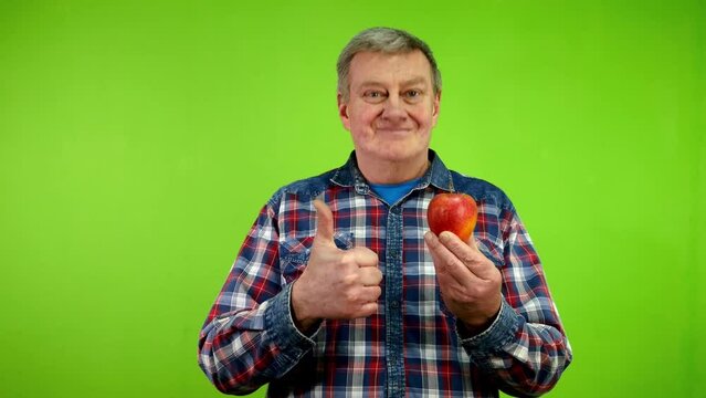 Man shows ripe apple and thumbs up, good fruit.