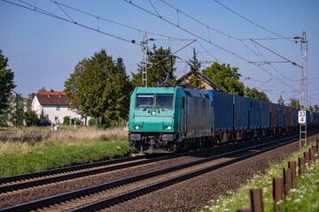 Fototapeta na wymiar A freight train runs on an electric railroad line near a settlement