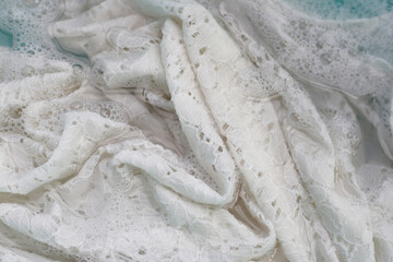 Women's lace dress soaked in water dissolved detergent with white foam bubble. Laundry concept