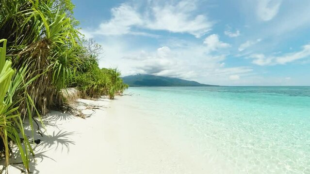 Mantigue Island with crystal water and ocean waves. Blue sky and clouds. Camiguin, Philippines.