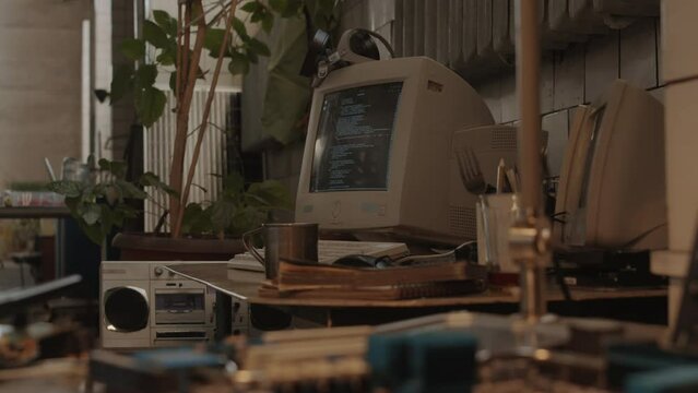 Old computer with programming code on screen in post apocalypse shelter with no people, circuit boards on table in defocused foreground