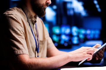 Certified electrician using tablet to examine blade servers for power fluctuations. Licensed...