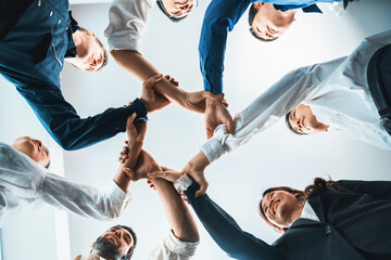 Business team joining hand in circular together symbolize successful group of business partnership and strong collective unity teamwork in diverse culture community workplace. Prudent
