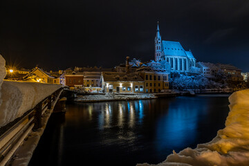Fototapeta premium Winter view of Cesky Krumlov, picturesque houses under the castle with snow-covered roofs. Narrow streets and the Vltava river. Travel and Holiday in Europe. UNESCO World Heritage. Czechia