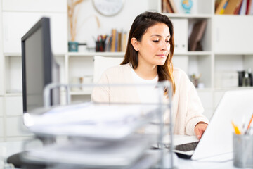 Woman sitting at workplace with computer in her office