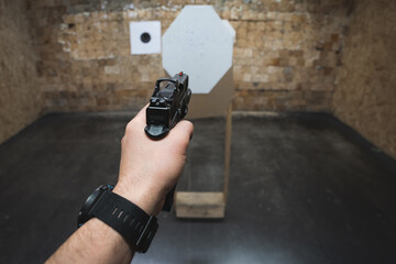 Tactical shooting from a pistol g19 with a red dot at targets in a shooting range.