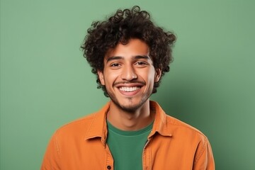 Fototapeta na wymiar Portrait of a happy young man with curly hair against green background