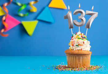 Birthday cupcake with candle number 137 - Blue background