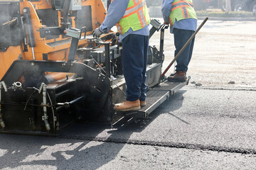 workers operate machinery for new asphalt