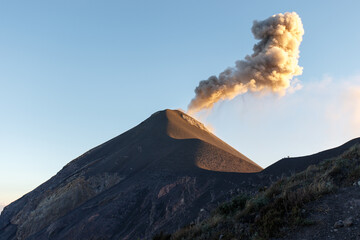 Volcan or volcano Fuego erupting with orange smoke column at sunrise, clear day near Antigua,...