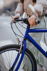 A partial view of a woman enjoying a bike ride in the city, featuring a close-up of a blue bicycle.