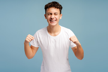 Excited strong teenager wearing stylish white t shirt rejoicing and supporting team
