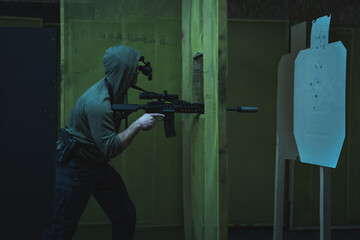 A man is engaged in tactical shooting from a silenced rifle with a night vision device mounted on...
