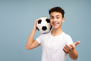 Portrait of smiling teenage boy holding ball playing football isolated 