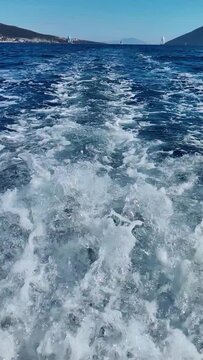 Close-up of waves coming out of the engine of a speeding boat. vertical video for social media. Slow motion 