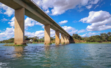 Photo of the large bases of the bridge over the São Francisco River seen from a boat and above beautiful blue sky with clouds.