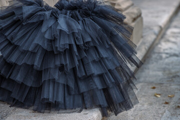 Black tutu laying on the stone stairs. Tulle ballerina skirt. Multilayered black skirt. Closeup....