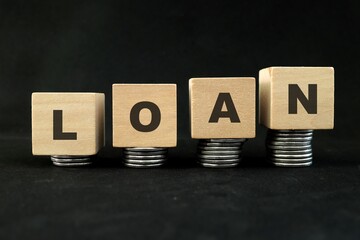 Increasing loan concept. Wooden blocks with increasing stack of coins in black background.