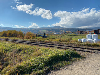 Helicopter preparing to take off from a field. Runway with landing area near a railroad. A helibell takes off near a railway in the mountains.
