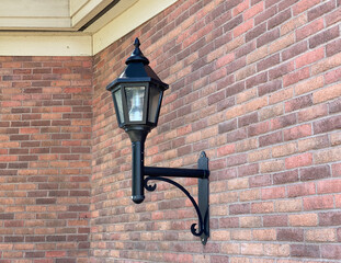 Old street lamp on a brick wall. Lamp post on the outside wall of a building. Vintage lantern.
