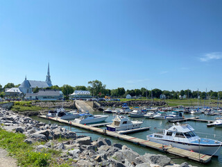 Boats in the town harbor, near a church and cemetery. Pier in the sea. Wooden dock on the shore....