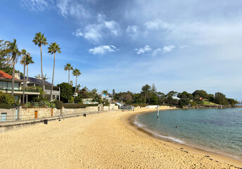 Beach with palm trees. Village houses on the shore with waves curling on the sand. 