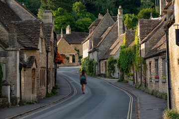 Female tourist visitor walking through picturesque village with old stone houses - obrazy, fototapety, plakaty