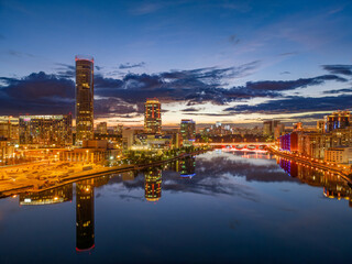 Fototapeta premium Yekaterinburg city and pond aerial panoramic view at summer or early autumn night. Night city in the early autumn or summer.