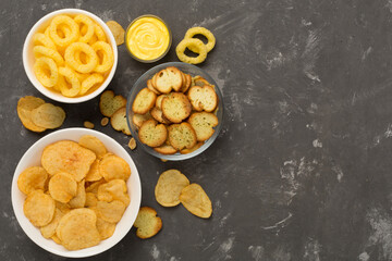 Different tasty snacks on concrete background, top view