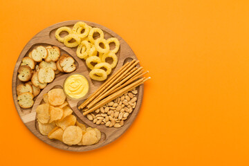 Different tasty snacks with sauce on color background, top view