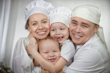 Cute oriental family with mother, father, daughter, son cooking in the kitchen on Ramadan, Kurban-Bairam, Eid al-Adha. Funny family at cook photo shoot. Pancakes, pastries, Maslenitsa, Easter