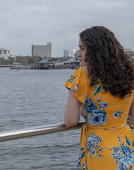 Hispanic young woman with curly long hair at lake side looking into distance