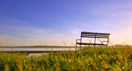 lonely bench in front of the lake, beautiful and peaceful landscape at sunset, copy space
