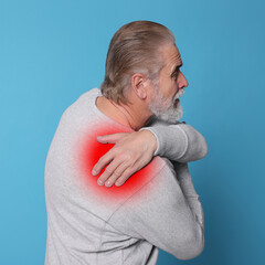 Senior man suffering from rheumatism on light blue background