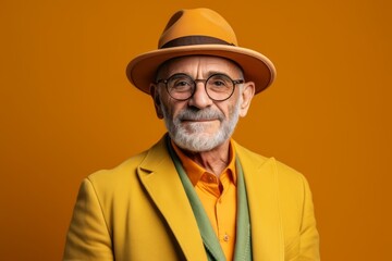 Portrait of an elderly man in a yellow jacket and hat on a yellow background