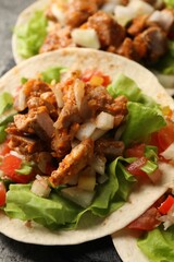 Delicious tacos with vegetables and meat on grey table, closeup