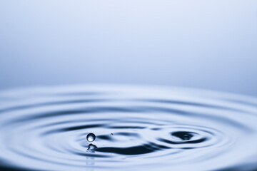 Splash of clear water with drops on light grey background, closeup