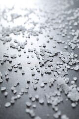Scattered white natural salt on black table, closeup