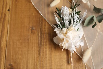 Stylish boutonniere and ribbon on wooden table, top view. Space for text