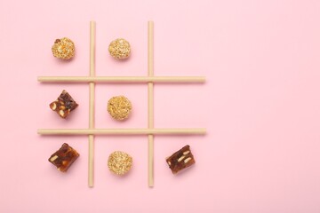 Tic tac toe game made with sweets on pink background, top view. Space for text
