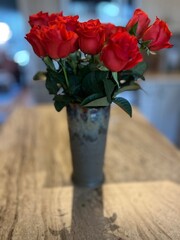 Gorgeous reddish orange roses in a vase on a counter.