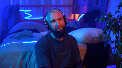 Music lover, young man in headphones, neon light portrait. Media. Relaxed guy in wireless...