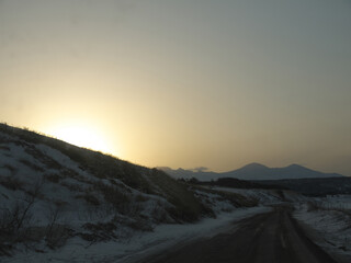 Fototapeta premium Driving in wilderness with sun rising over mountain ridge on Iturup, Kuril islands