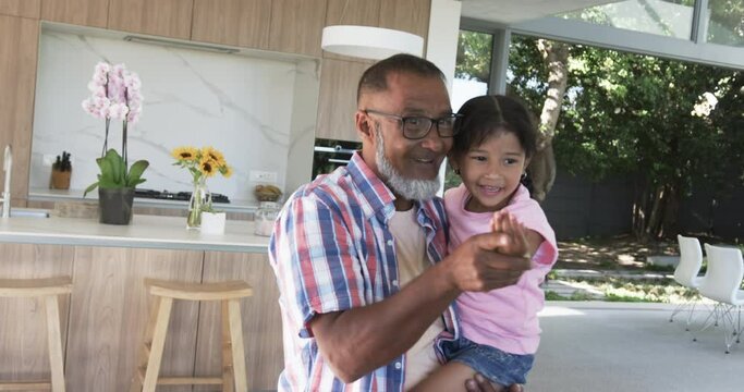 Biracial grandfather and his granddaughter share a joyful moment in a modern kitchen