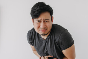 Asian man in black t-shirt feeling sick and stomach ache isolated on white wall.