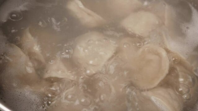 Boiling homemade meat dumplings, closeup. Cooking Russian traditional meal