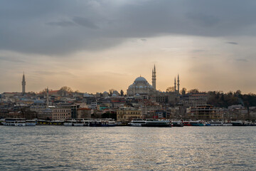 Fototapeta premium View of the Fatih district in Istanbul from the waters of the Golden Horn Bay and the Suleymaniye Mosque against the sunset sky, Istanbul, Turkey