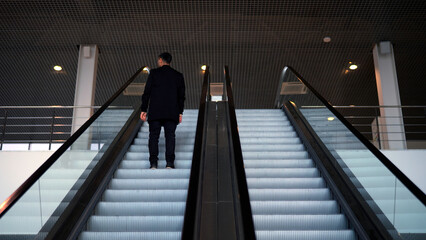 Passenger riding on the escalator up to the station of the ground metro. Media. Rear view of a...